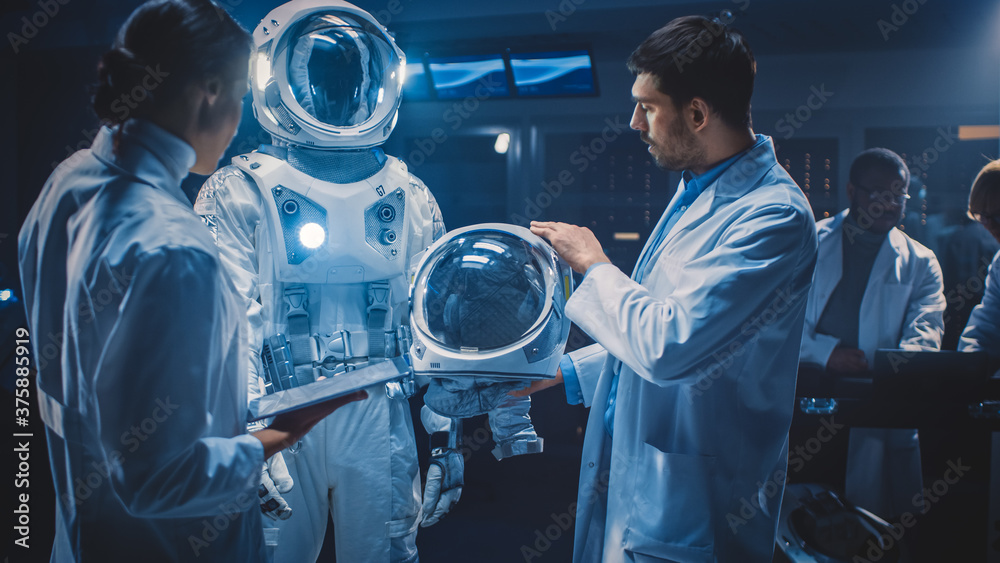 Diverse Team of Aerospace Scientists and Engineers Wearing White Coats have Discussion, Use Computer