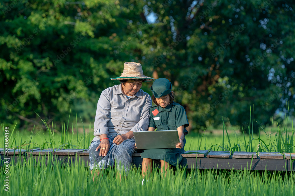 Girl scouts and mother sitting using laptop at countryside.