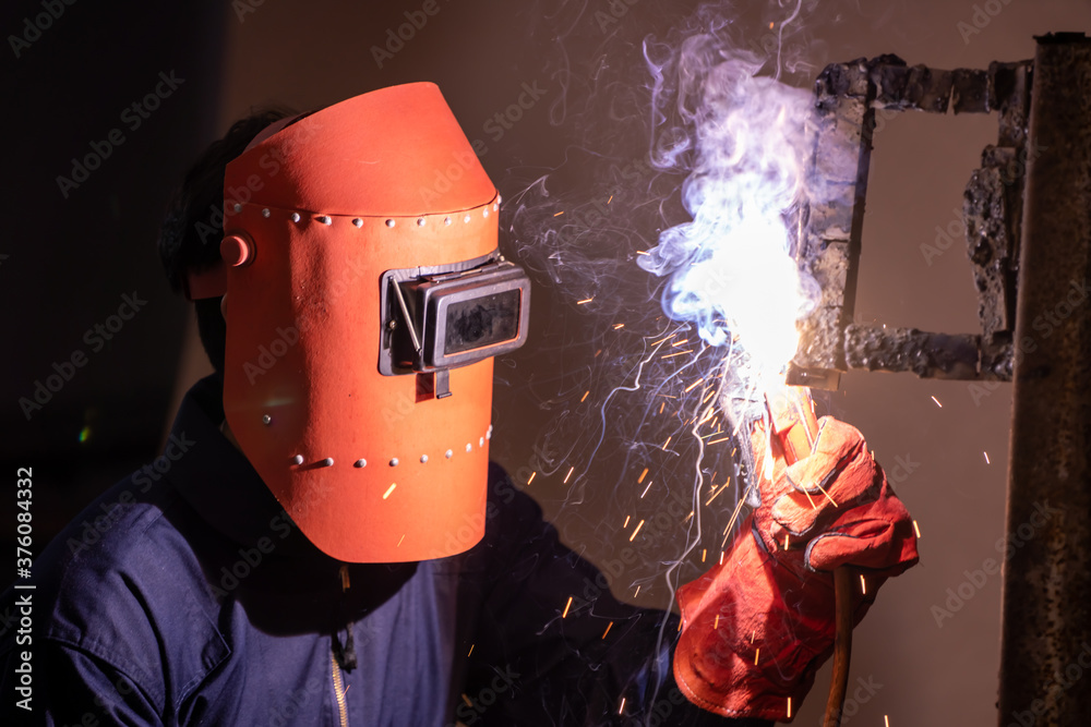 Metal welding steel works using electric arc welding machine to weld steel at factory. Metalwork man