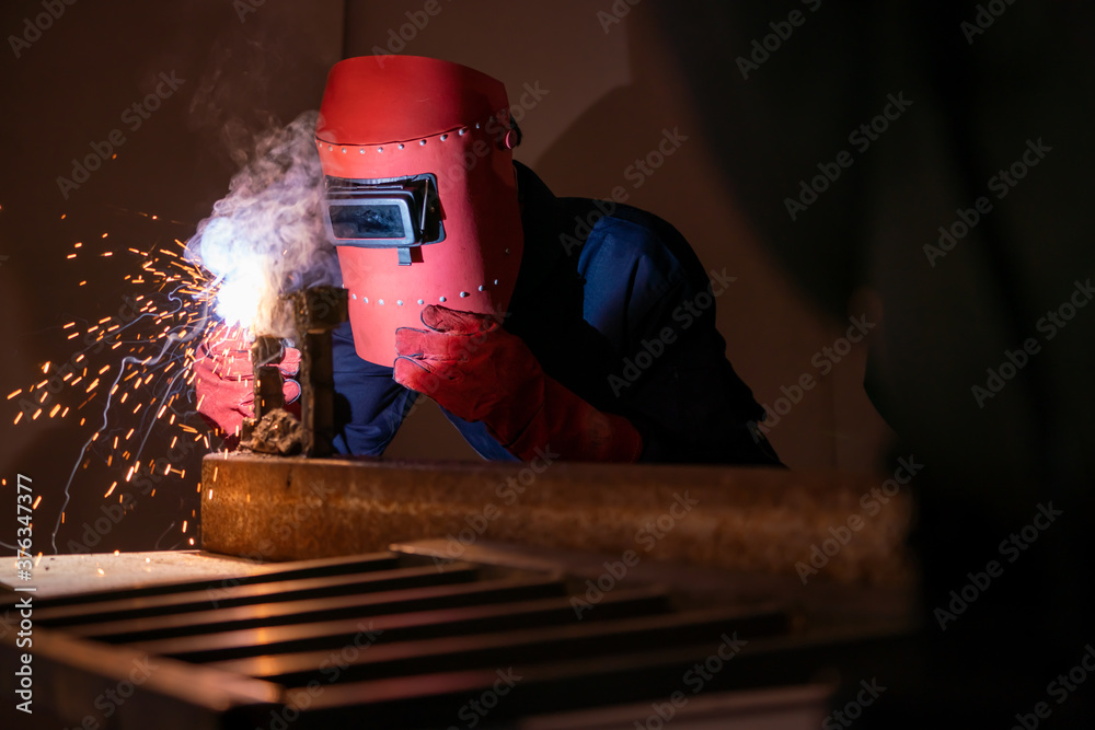 Metal welding steel works using electric arc welding machine to weld steel at factory. Metalwork man