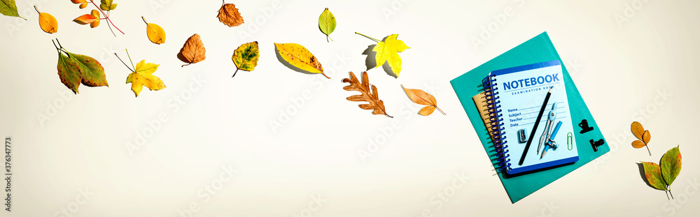 Notebooks with school supplies and autumn leaves - flat lay