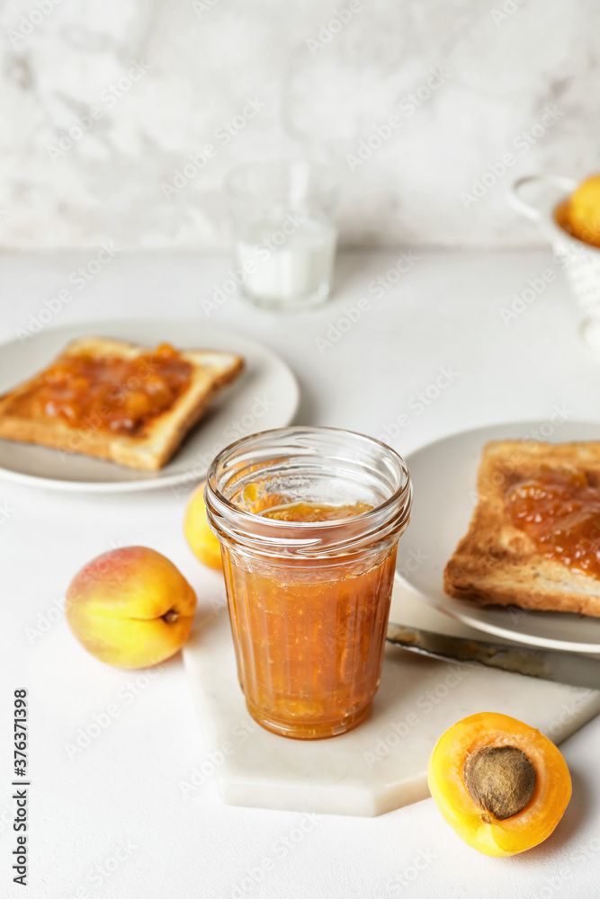 Jar of tasty apricot jam and toasted bread on table