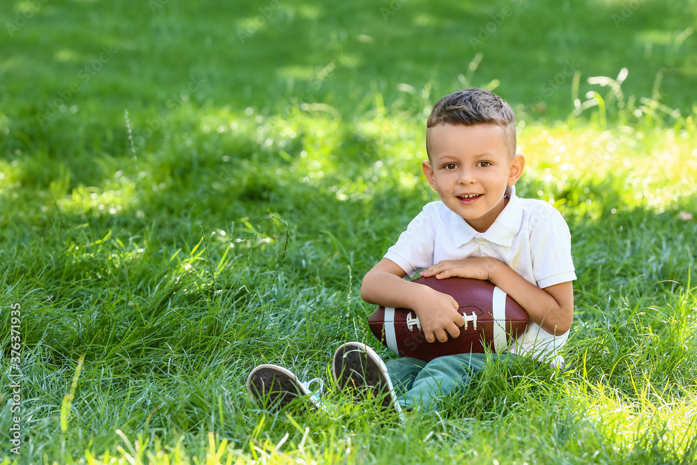 Little boy with rugby ball outdoors