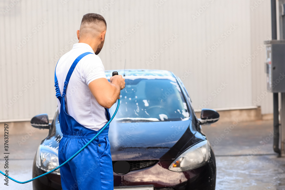 Male worker washing car outdoors