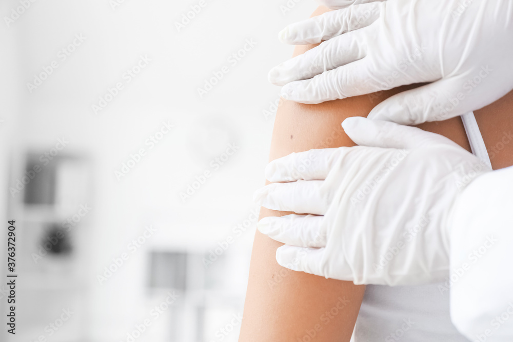 Dermatologist examining patient in clinic, closeup