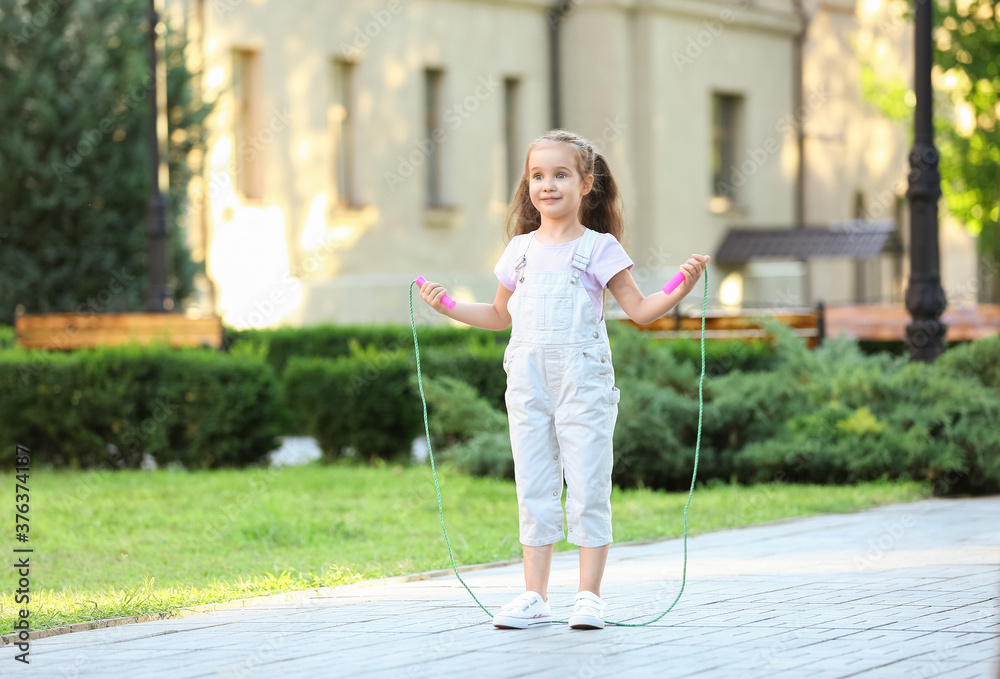 Cute little girl jumping rope outdoors