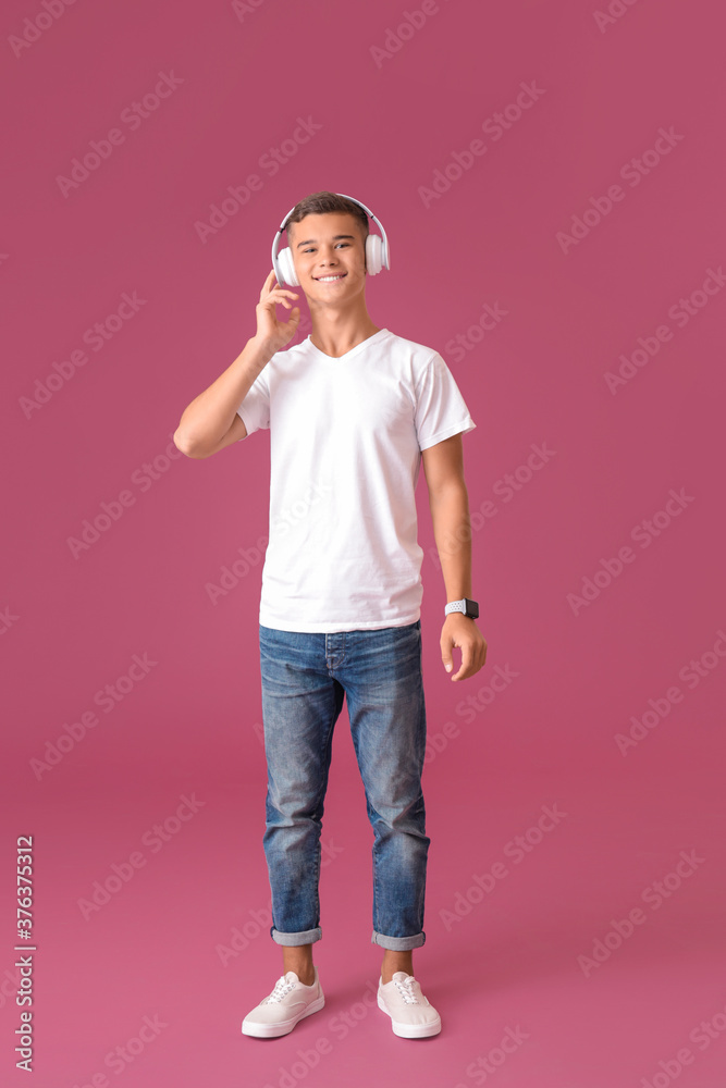 Teenage boy listening to music on color background