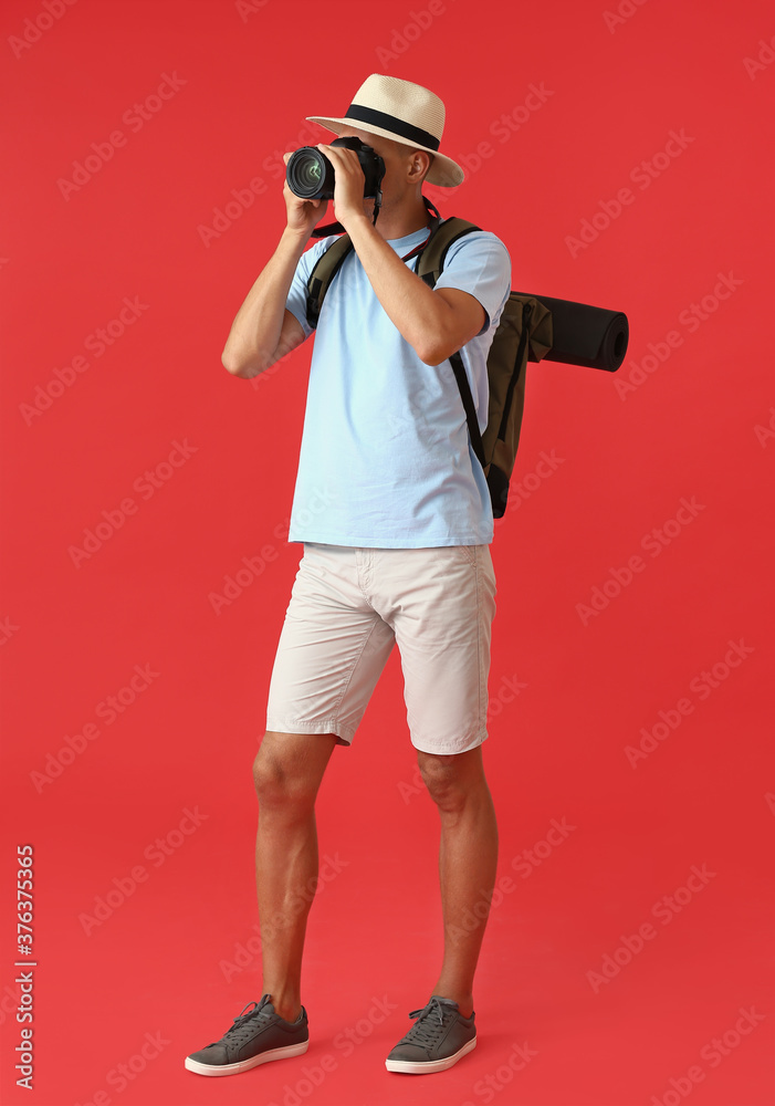 Male tourist taking photo on color background