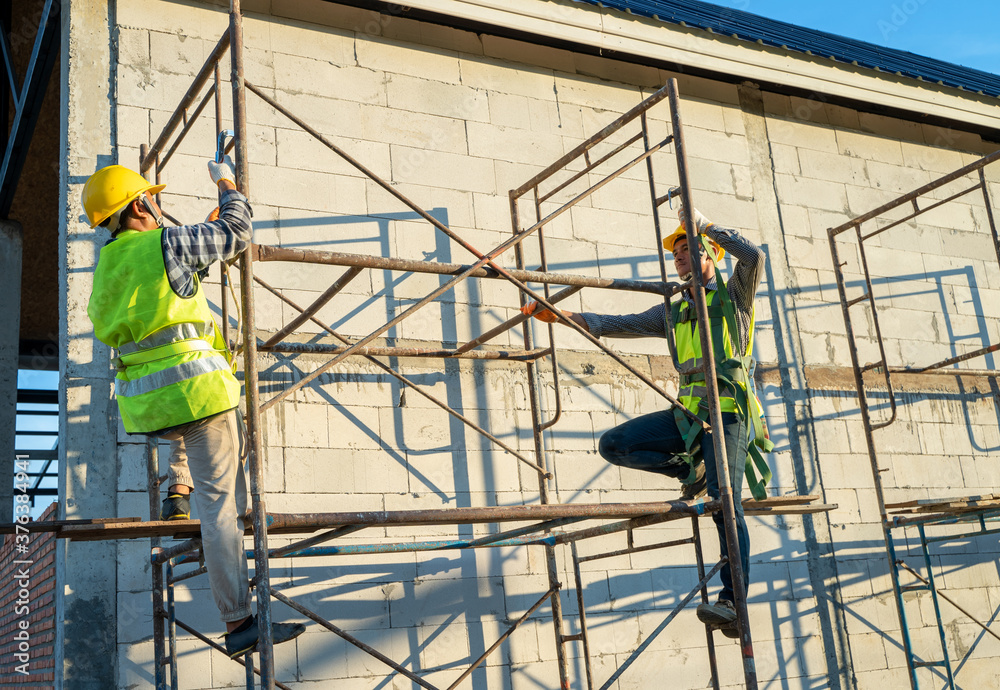 Professional worker wearing safety harness and safety line working on scaffolding at construction si