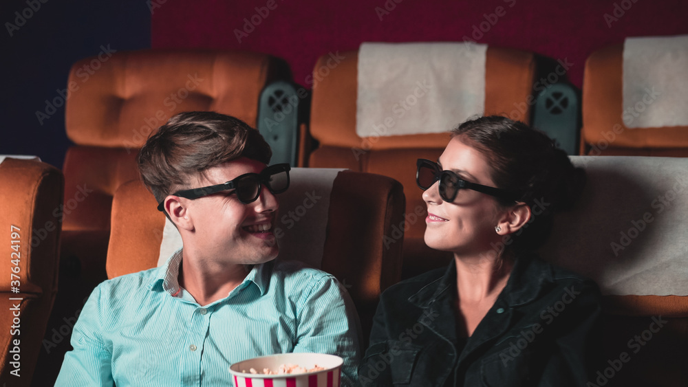 Man and woman in the cinema watching a movie with 3D glasses. with interest looking at the screen, e