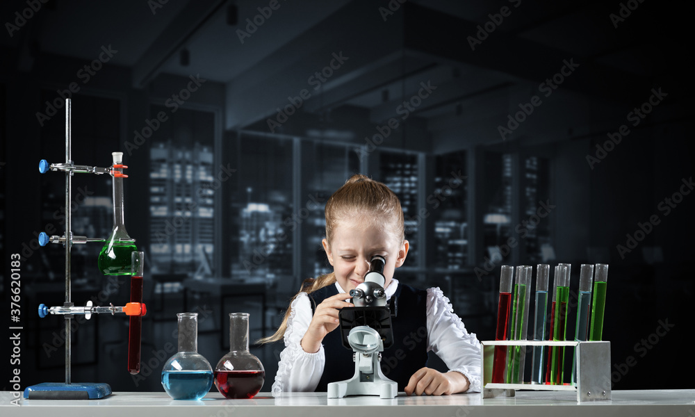 Little girl scientist looking through microscope