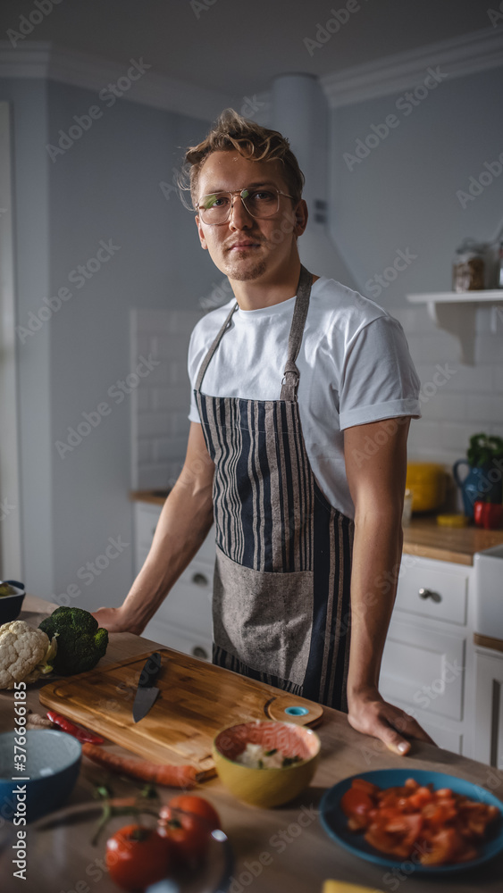 Handsome Man in White Shirt and Apron is Making a Healthy Organic Salad Meal in a Modern Sunny Kitch