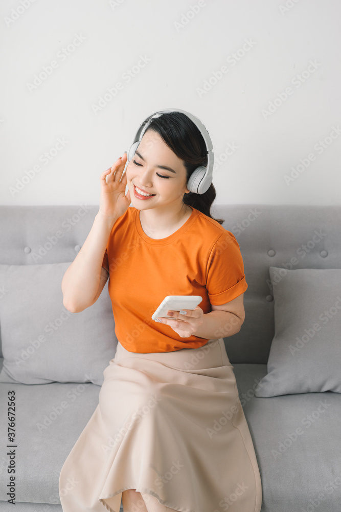 Asia woman listening music in earphones on sofa