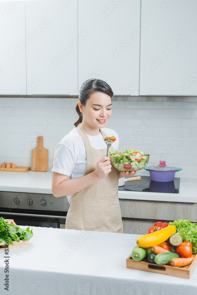 年轻女人吃沙拉，拿着一份混合的