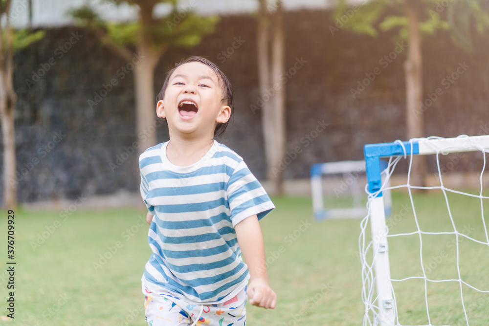 亚洲蹒跚学步的男孩在户外足球场公园踢足球。3岁亚洲男孩ki