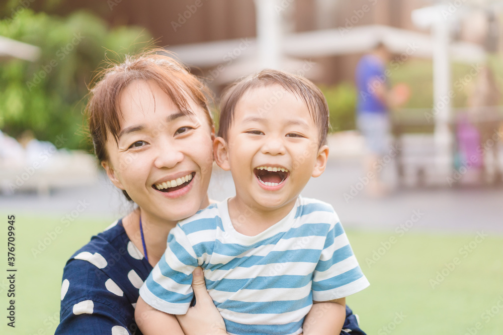 亚洲母亲和蹒跚学步的男孩一起玩耍的画像。快乐的儿子和妈妈大笑