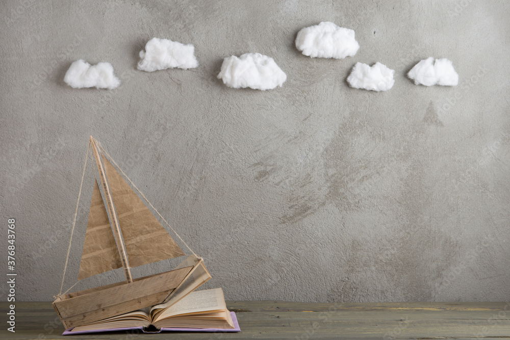 Education is a journey concept, toy boat and books like a sea waves on the wooden table, inspiration