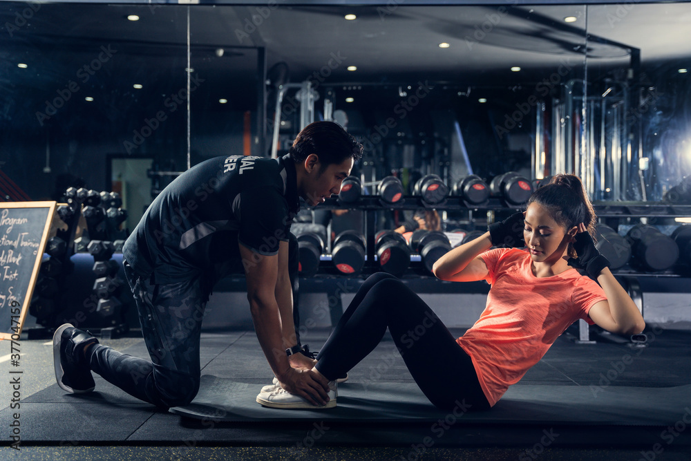 Personal trainer to practice sit-ups in the gym