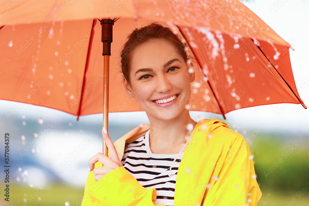 美丽的年轻女子，带着雨伞，在户外穿着雨衣