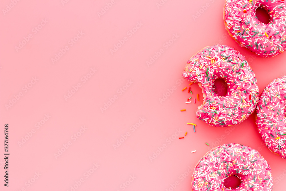 Pink berry donuts flat lay, top view. Glazed and sprinkles doughnuts