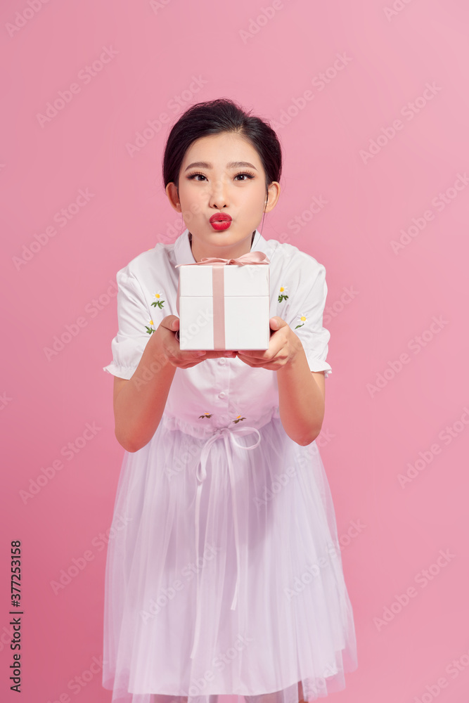 Girl received a gift. Girl blows a kiss. Portrait, pink background