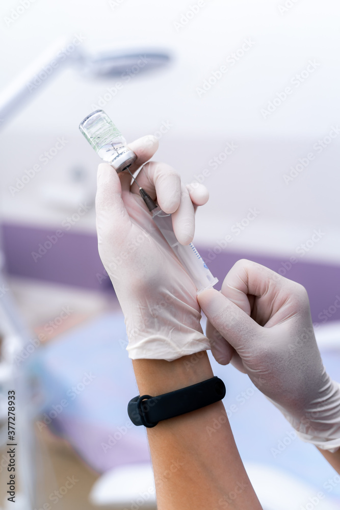 Syringe in nurse`s hands. Blurred background. Selective focus on hands with syringe. White gloves. B