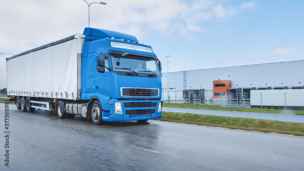 Long Haul Semi-Truck with Cargo Trailer Full of Goods Travels on the Highway Road. Daytime Driving A