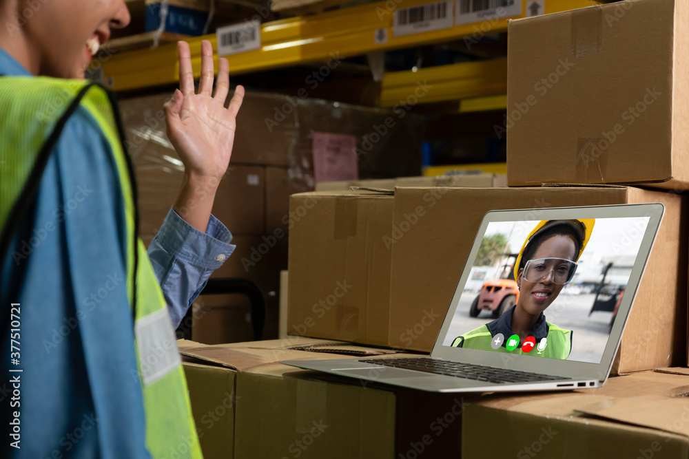 Warehouse staff talking on video call at computer screen in storage warehouse . Online software tech