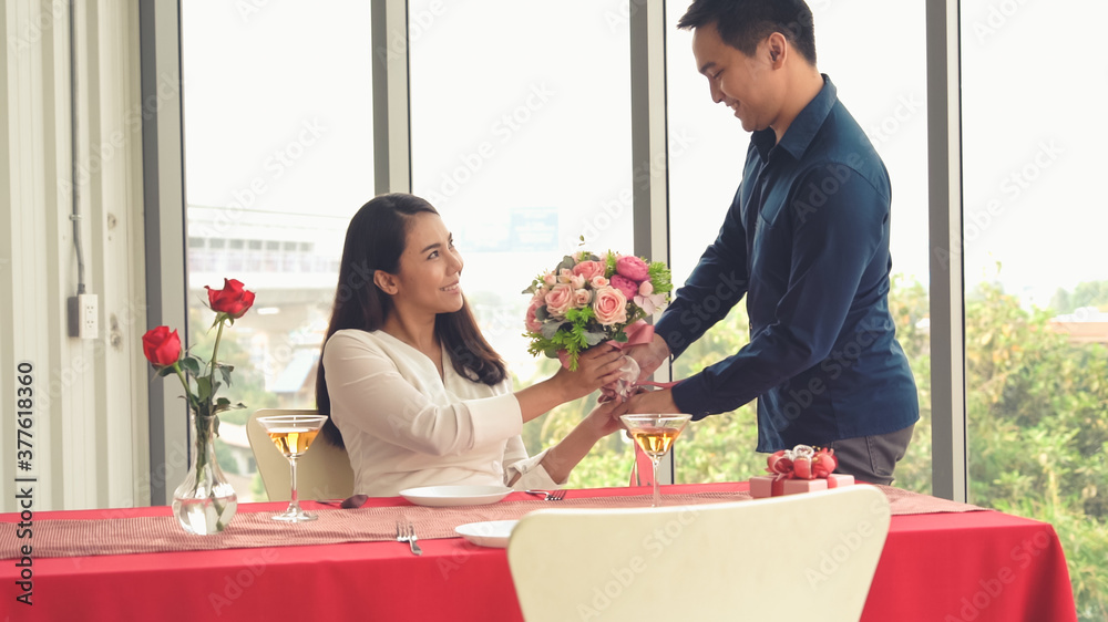 Romantic couple giving gift to lover at restaurant . Happy couple lifestyle .