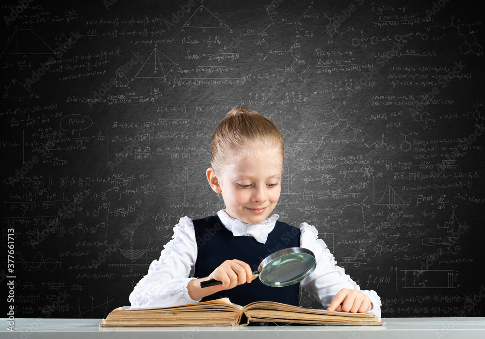 Little girl sitting at desk with magnifier