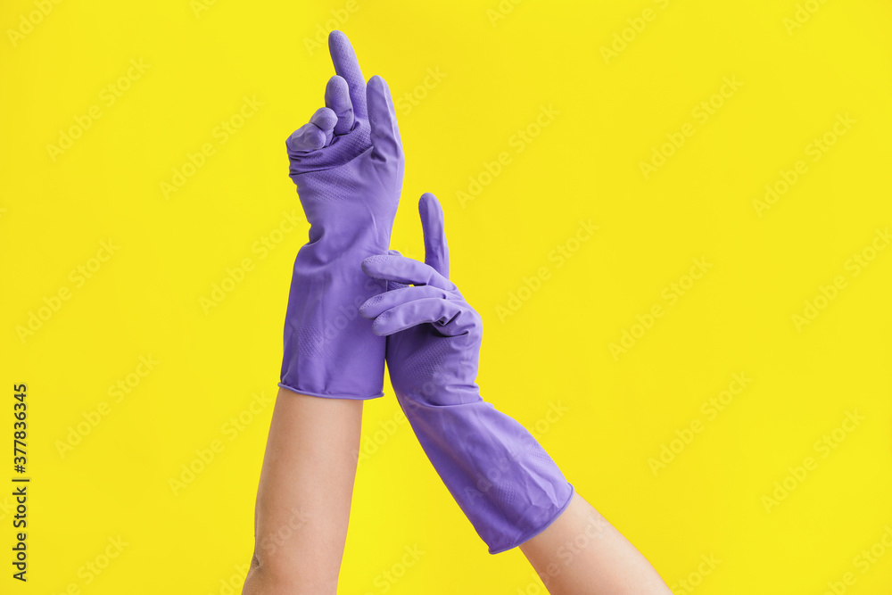 Hands in rubber gloves on color background