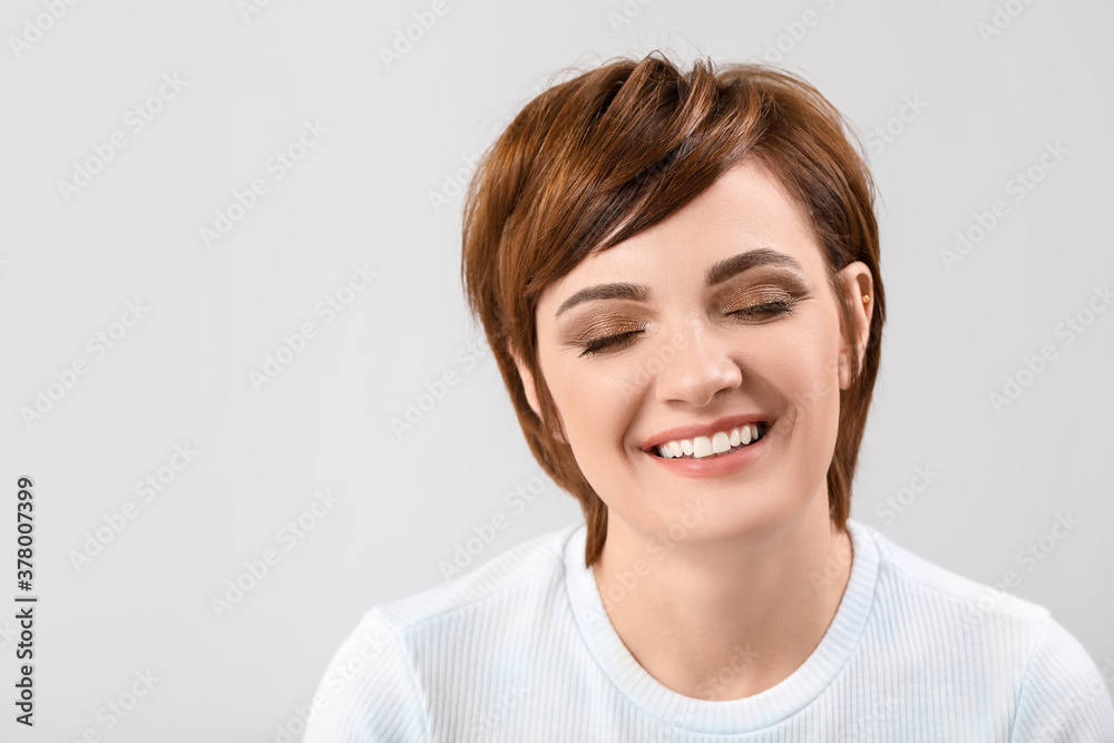 Young woman with beautiful short hair on grey background