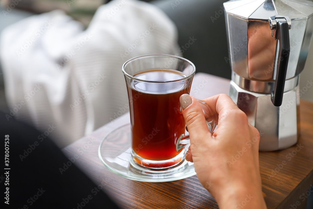 Woman with cup of coffee resting on sofa at home