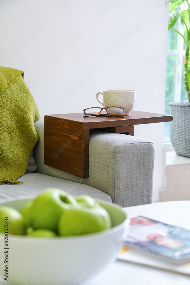 Cup with eyeglasses on armrest table in room