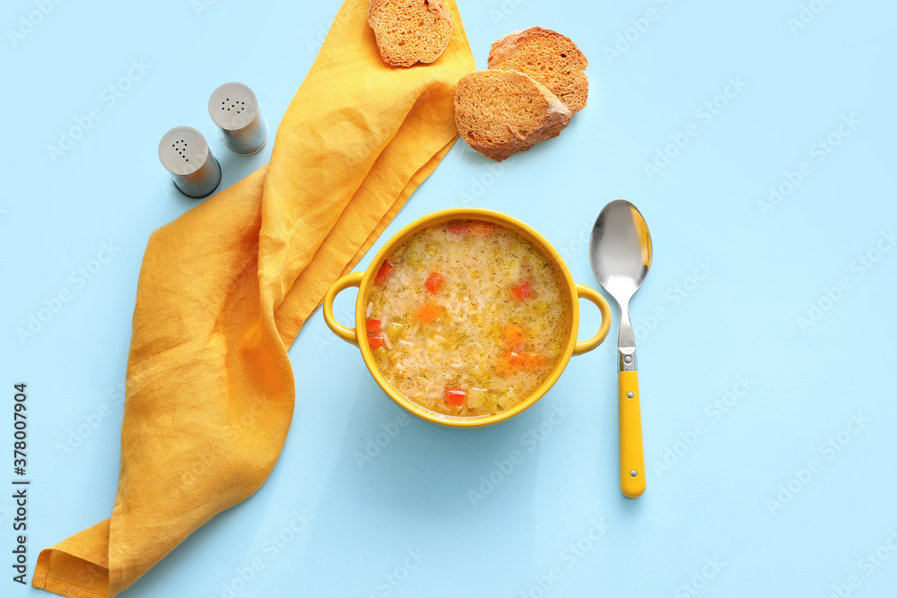 Pot of tasty rice soup on color background