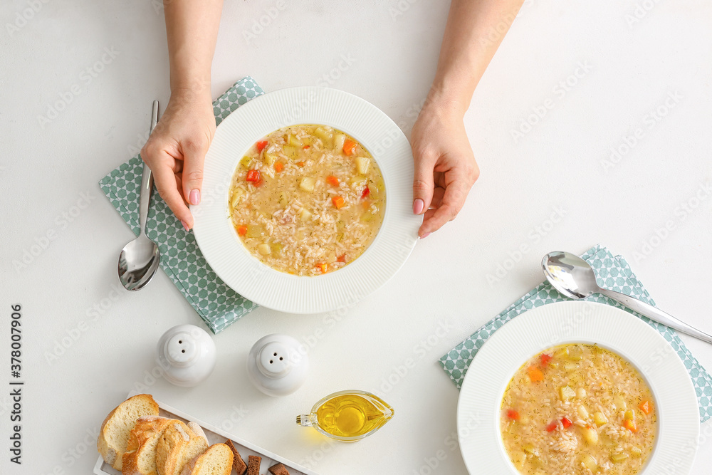 Woman with tasty rice soup at table