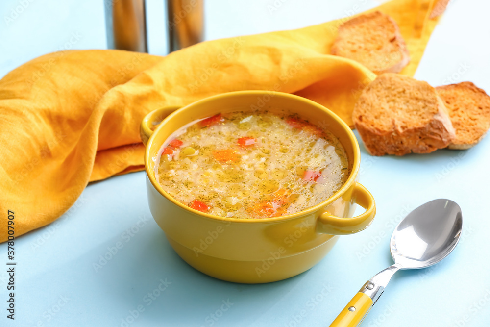 Pot of tasty rice soup on color background