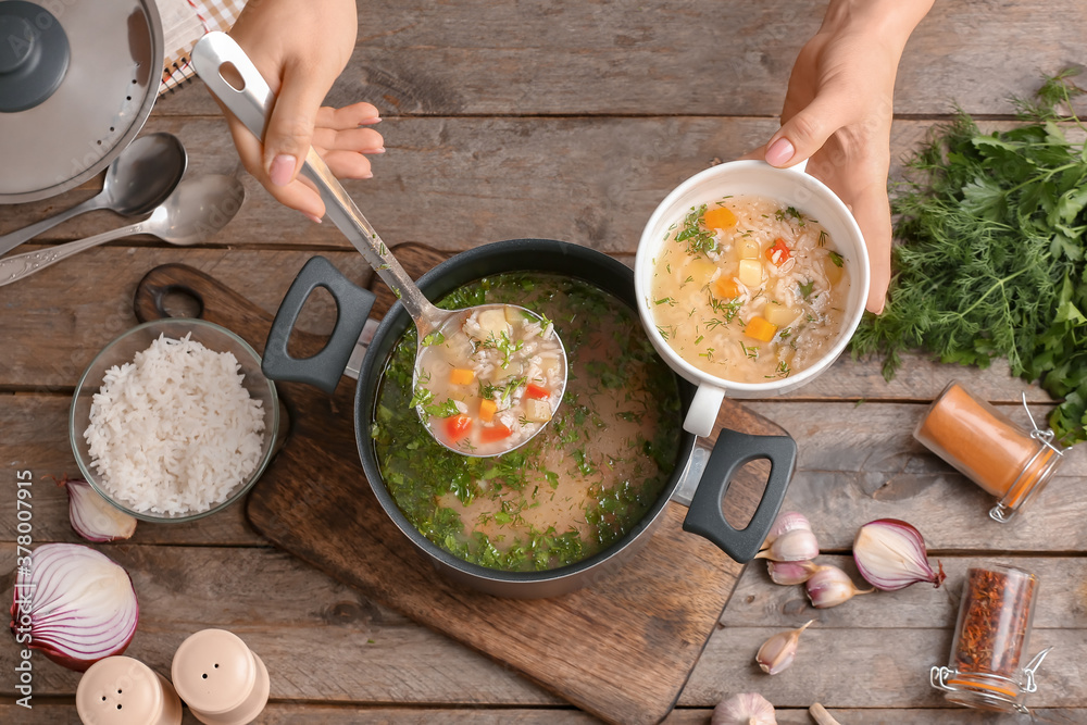 Woman pouring tasty rice soup from pot