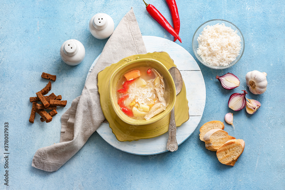 Bowl of tasty rice soup on color background