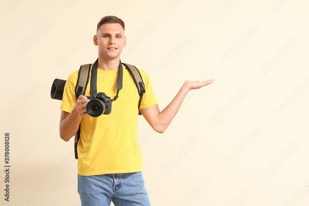 Male tourist with camera on color background