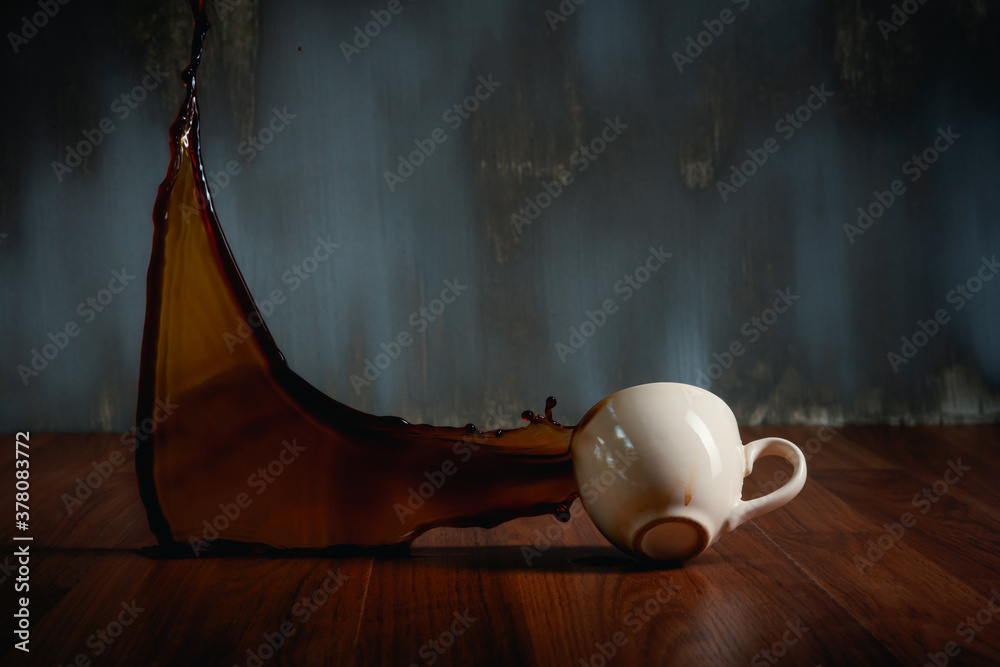 hot coffee cup spilling onto the wooden floor and coffee water splash on dark background