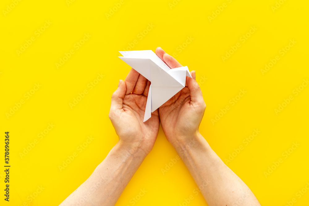 Origami bird in female hands. Care peace concept. Top view