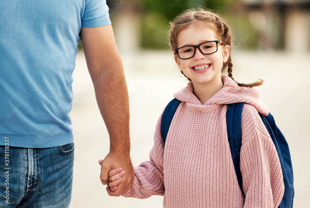 first day at school. father leads  little child school girl in first grade.