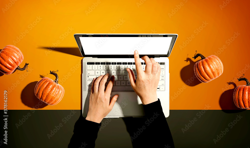 Autumn pumpkins with person using a laptop computer from above