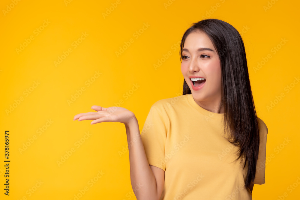 Happy beautiful young asian woman with yellow background holding copy space imaginary on beauty palm