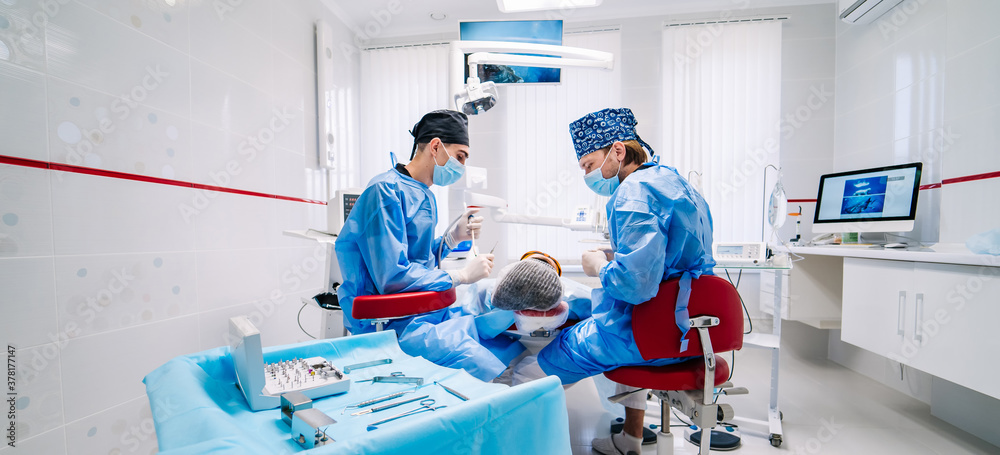 Two dentists examine patients teeth in modern stomatology clinic. Selective focus from the side. Den