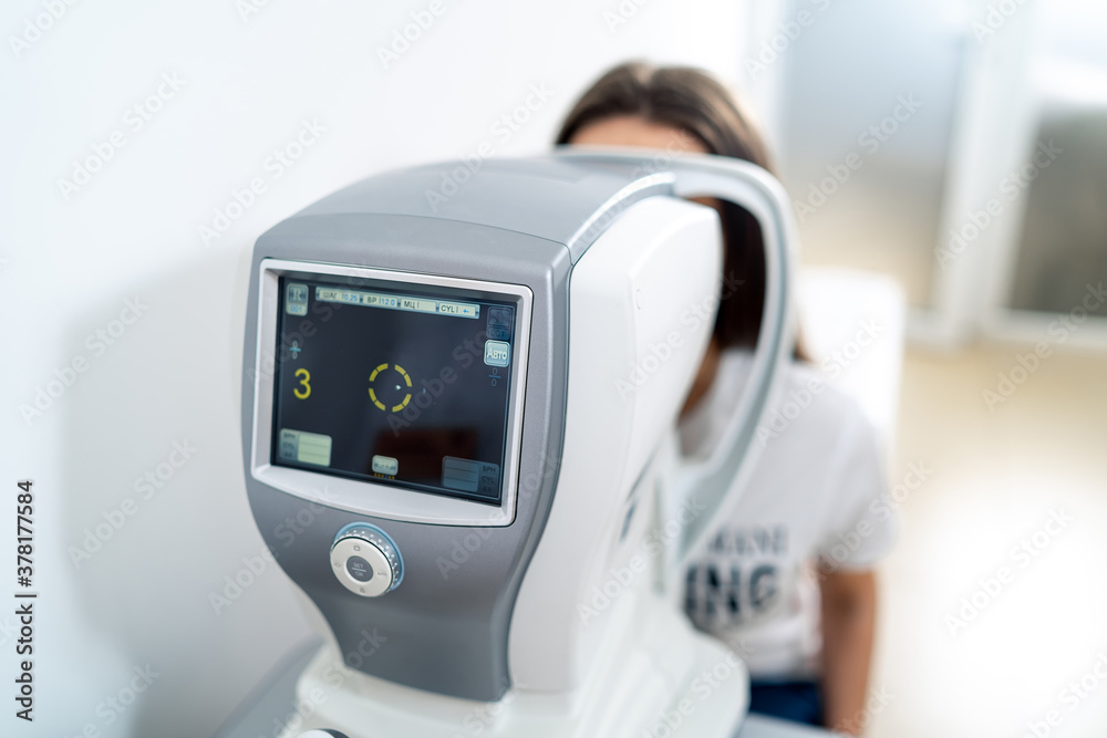 Optometrist in exam room. Special equipment for eye sight testing. Modern ophtalmology clinic.