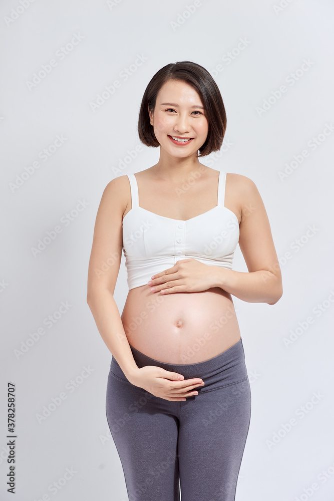 A beautiful Asian woman standing touching her belly. Pregnancy and expectation concept