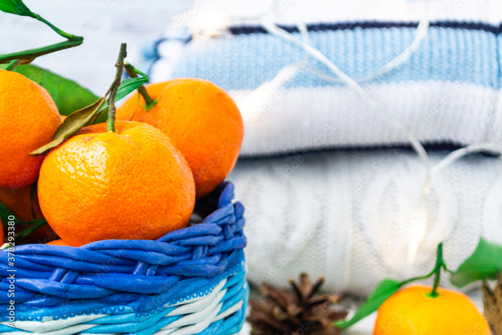 Christmas basket with tangerines, cinnamon sticks and pine cones lie on a wooden white background. K