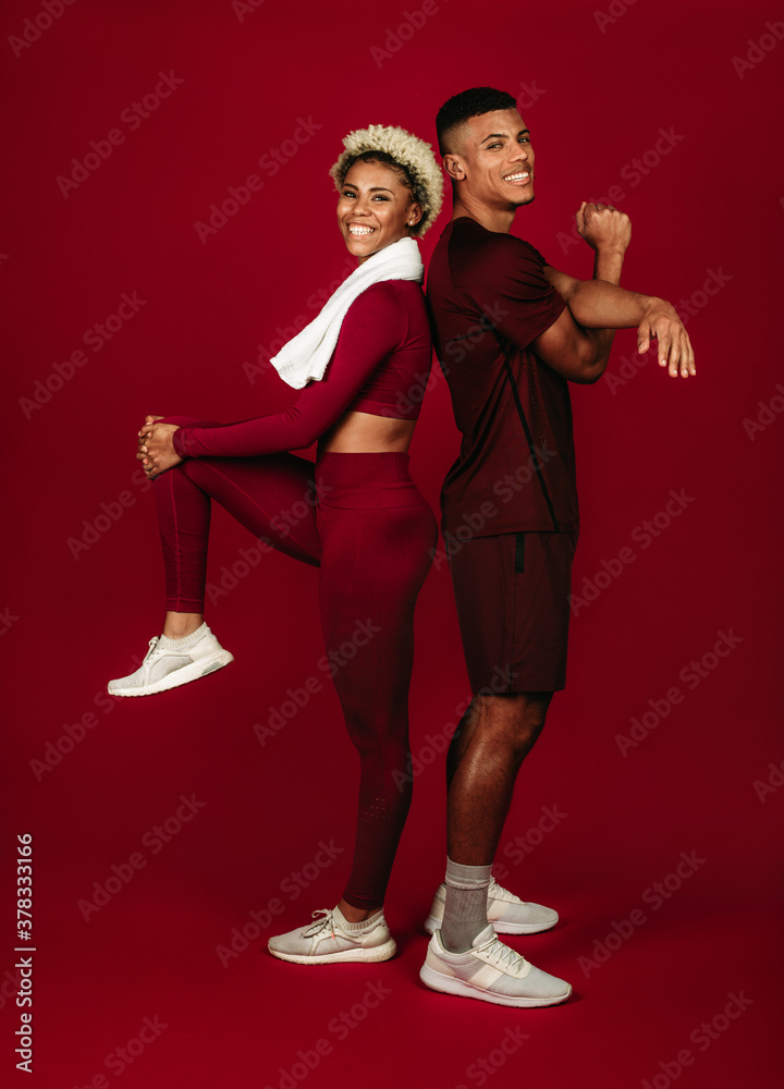 Cheerful fitness couple working out on maroon background